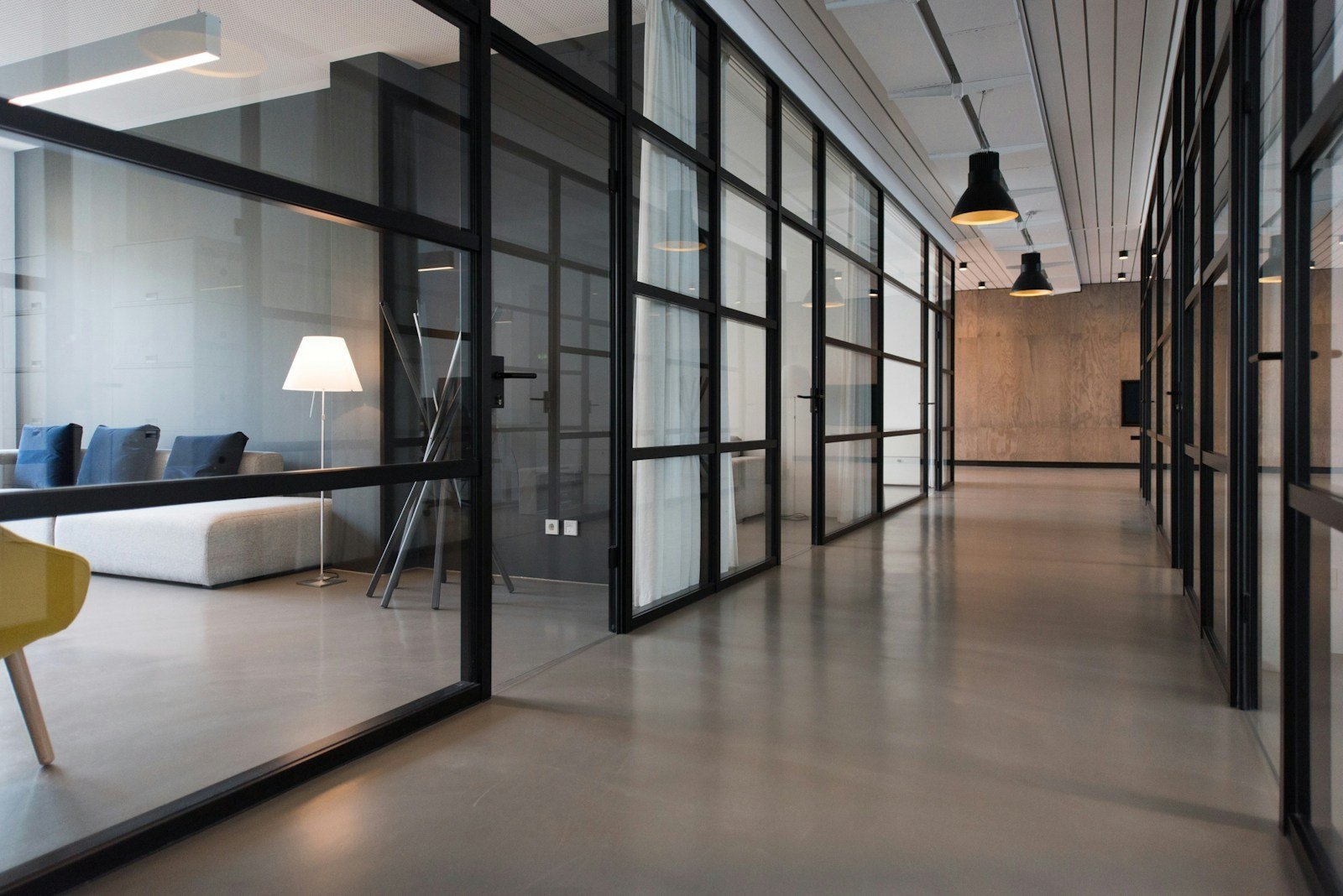 Bright office corridor with glass partitions and exposed ceiling services